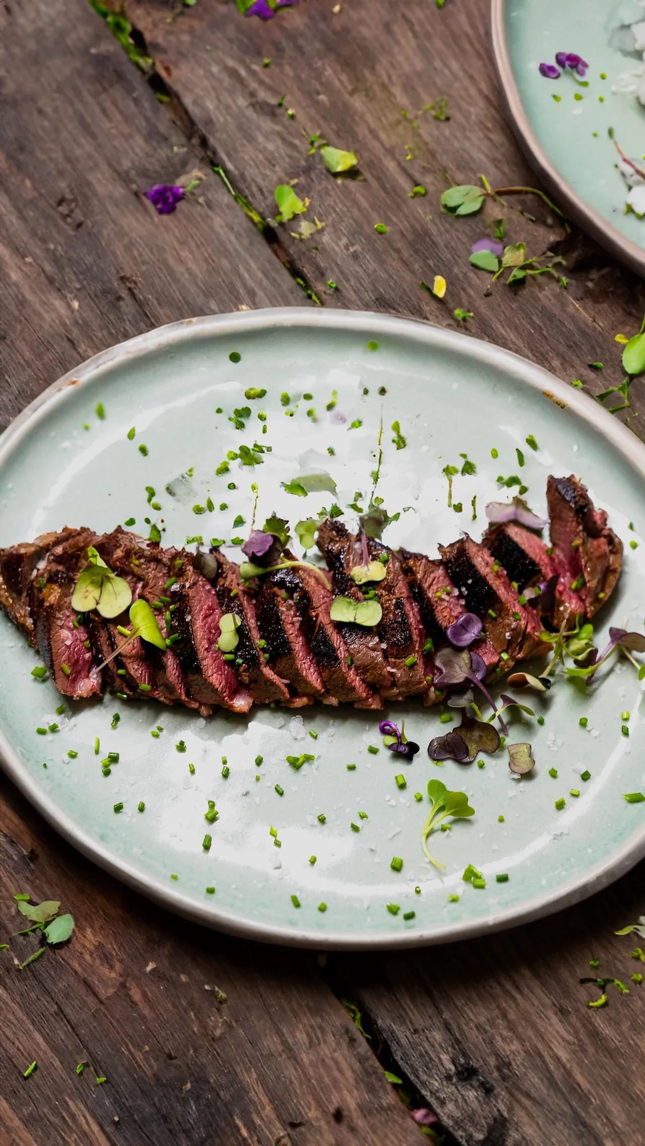 Sliced grilled steak garnished with herbs on a plate