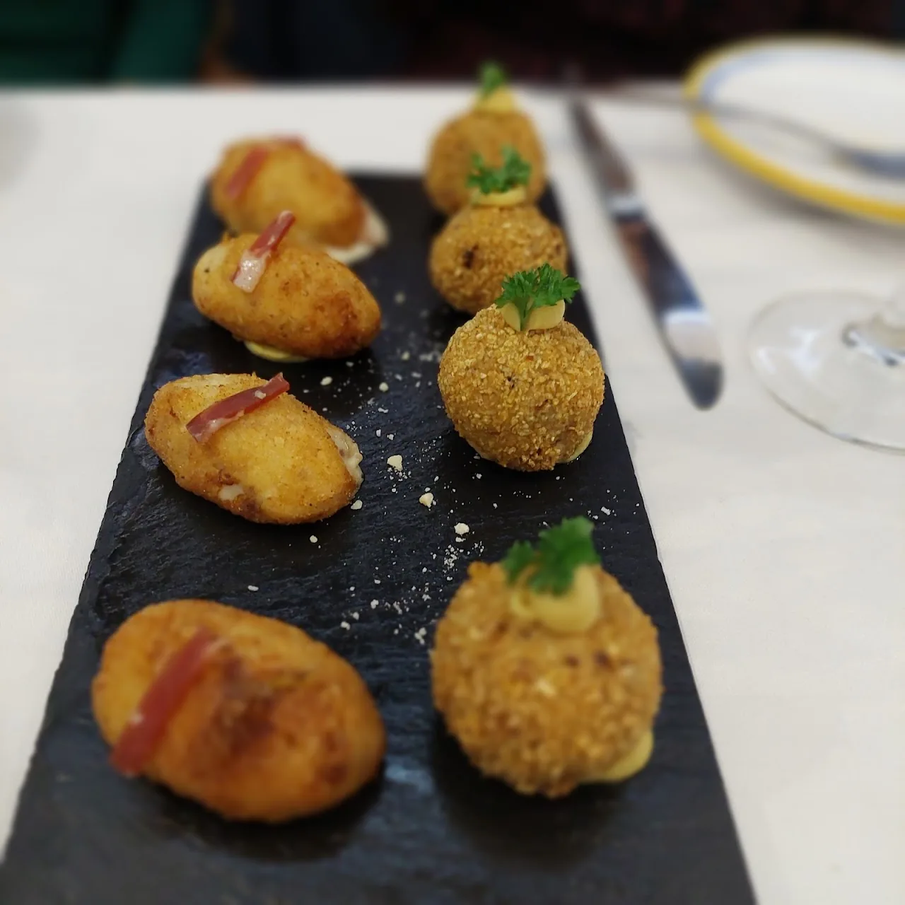 A slate board of breaded croquettes garnished with herbs