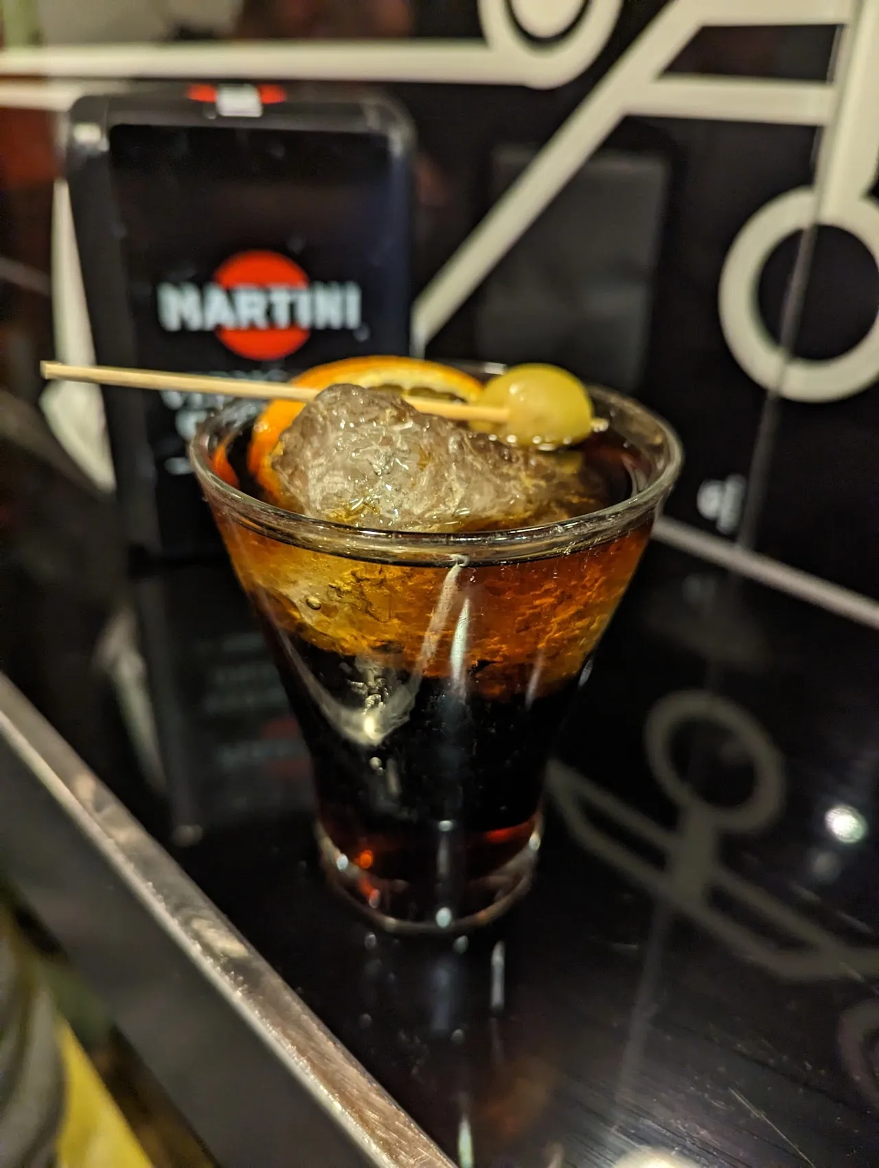 A martini-style cocktail garnished with an olive and citrus twist