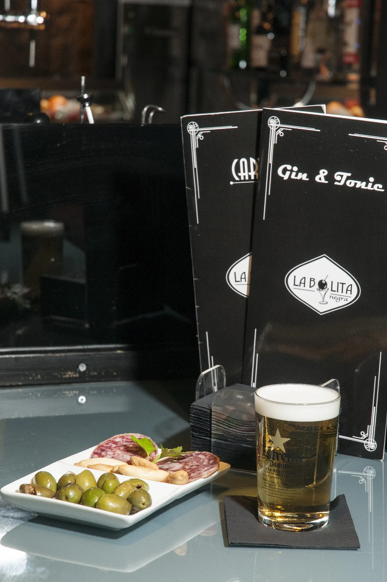 A small plate of olives beside a glass of beer