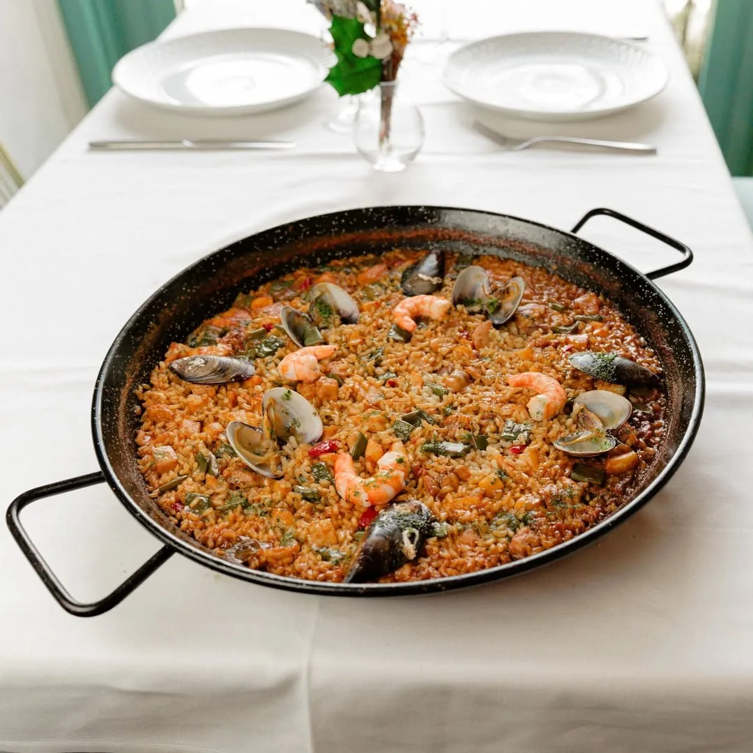 A pan of seafood paella with shrimp and mussels on a set table
