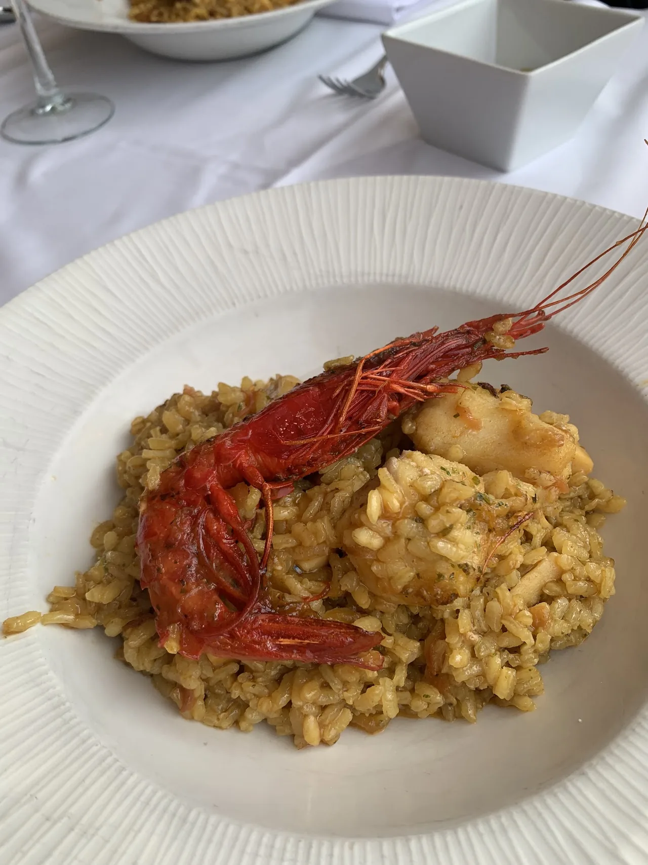 A plate of rice with a large shrimp and seafood