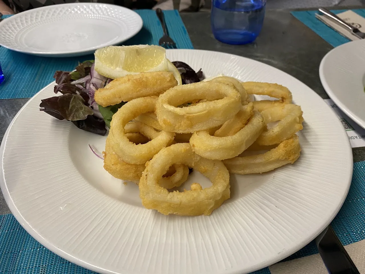 A plate of fried calamari rings with mixed greens