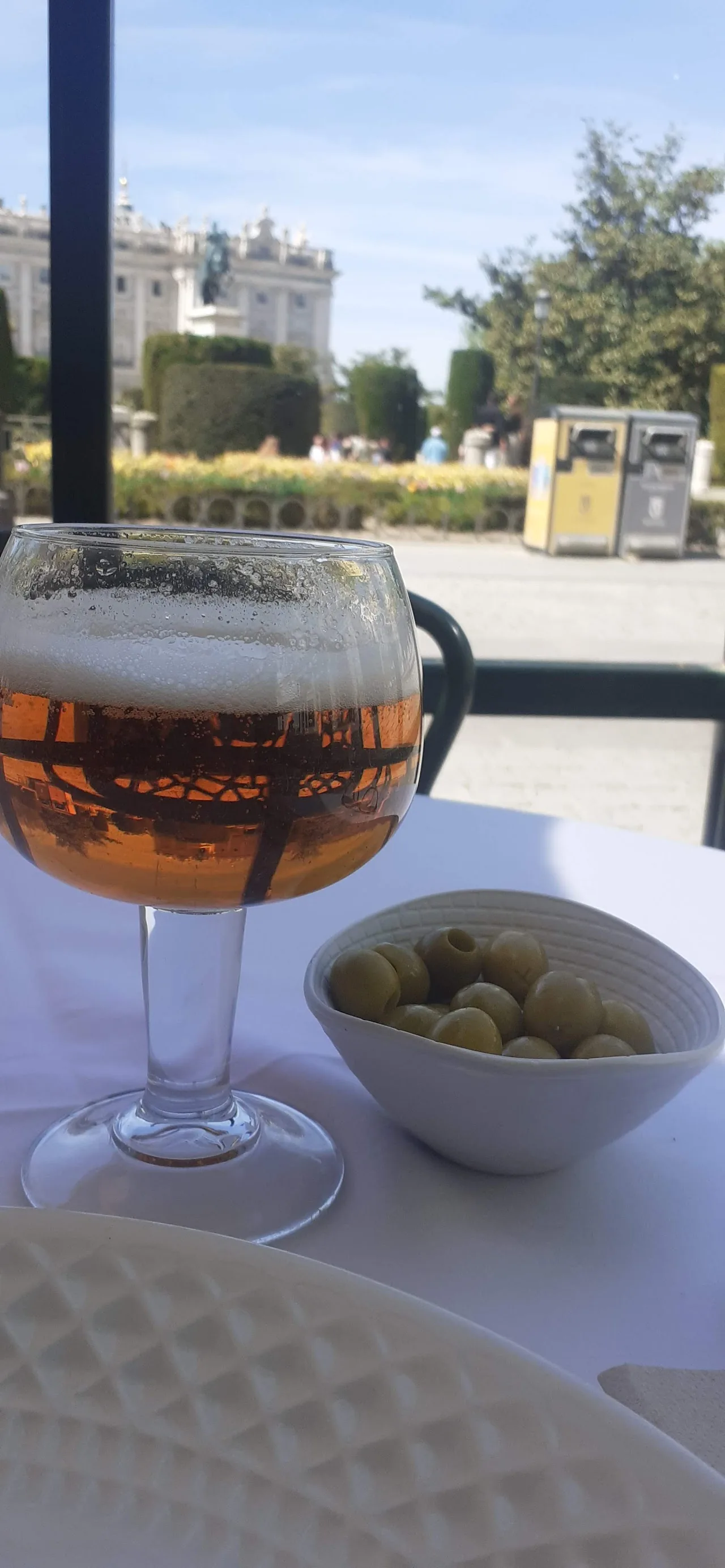 A glass of rose wine beside a small dish of olives