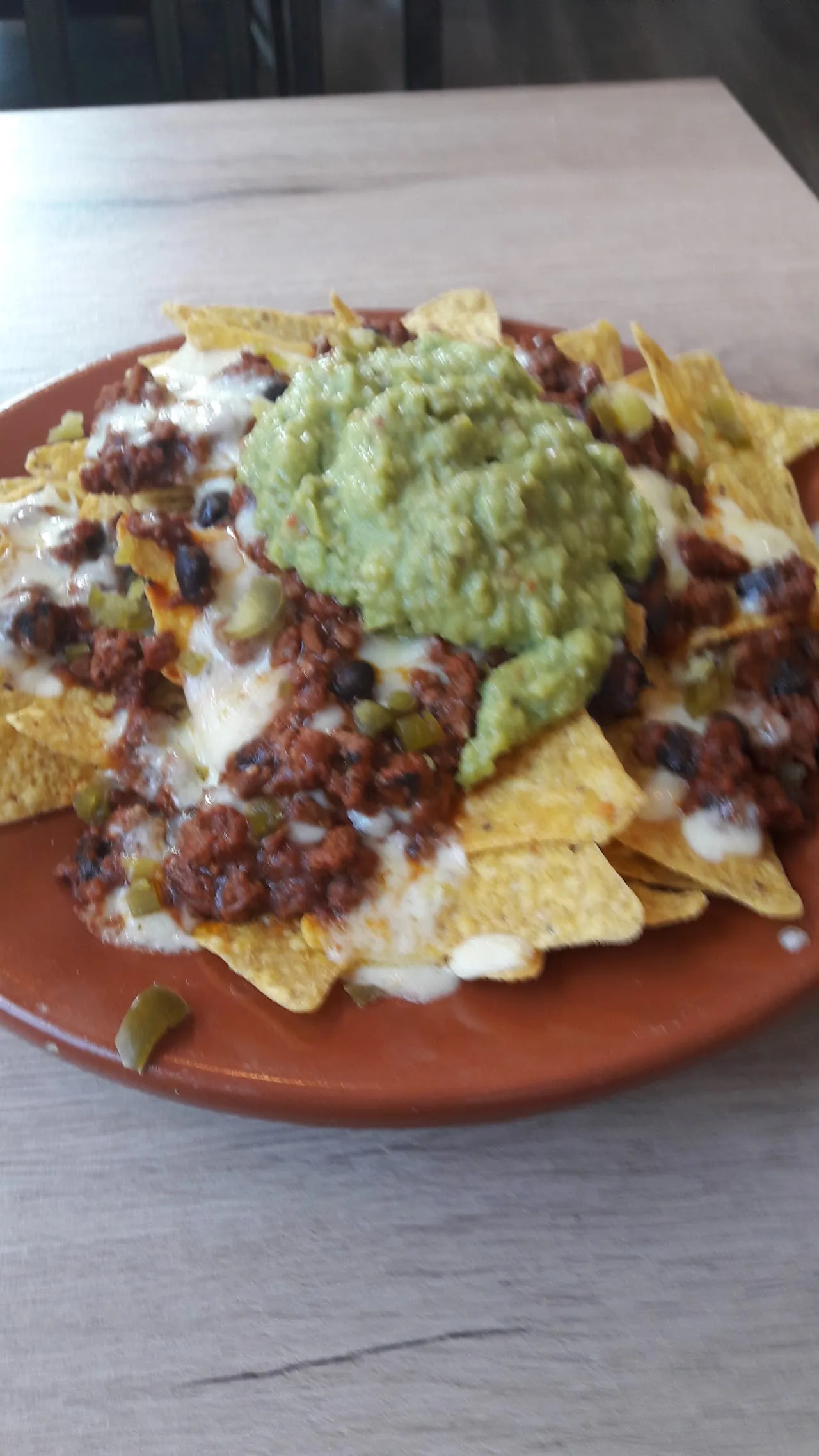 A plate of nachos topped with chili and guacamole