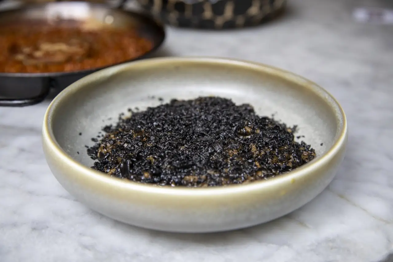 Squid-ink black rice served in a stoneware bowl on a marble counter