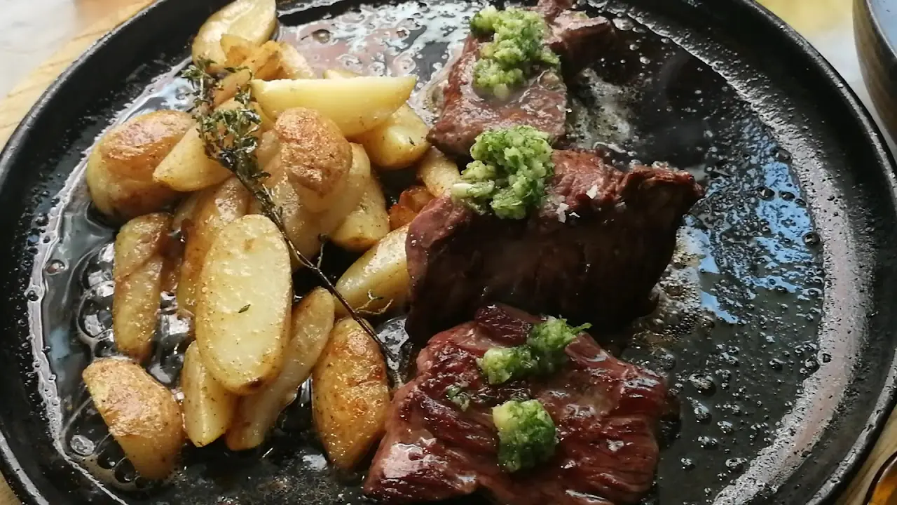 Seared steak with roasted potato wedges in a black pan