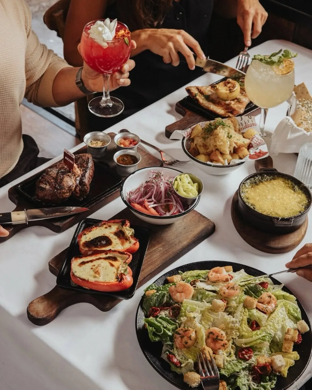 A table with grilled meat, a salad and several shared dishes