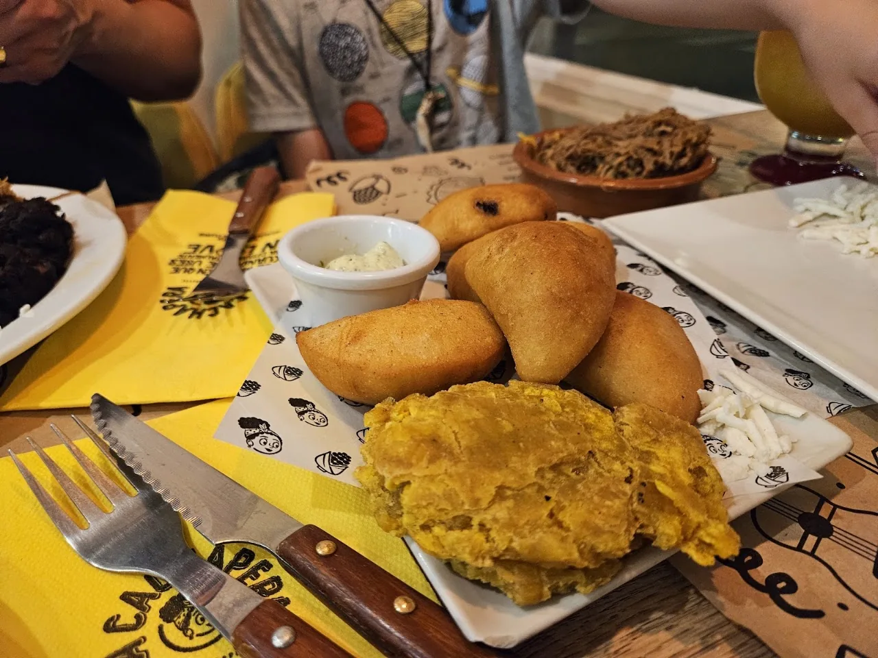 A plate of fried empanadas and fried plantain chunks with a dipping sauce