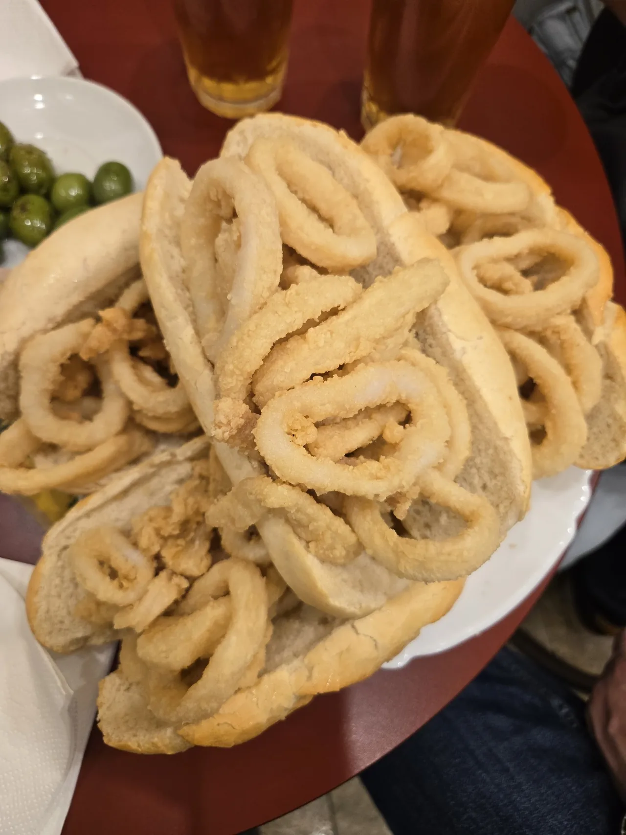 A roll piled with fried squid rings on a white plate
