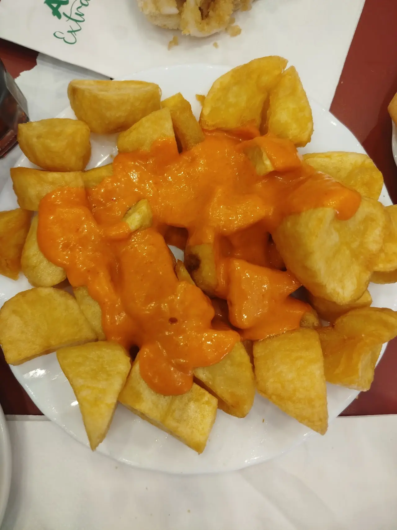 A plate of patatas bravas topped with spicy orange sauce