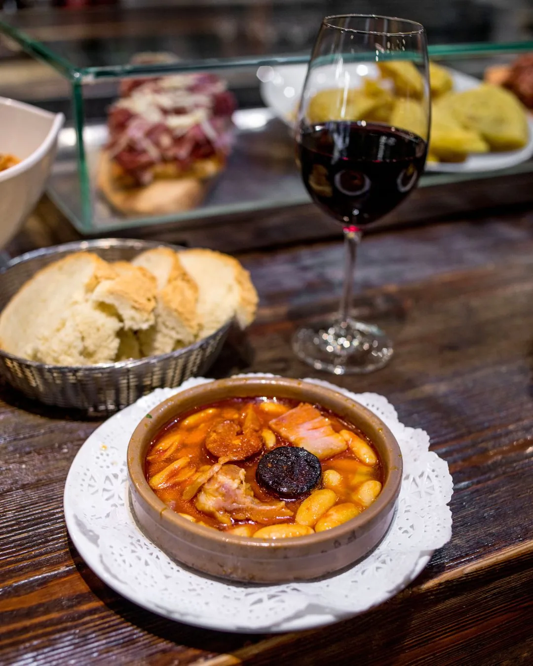 Fabada asturiana, a clay dish of white beans with chorizo, morcilla and pork, with bread and red wine