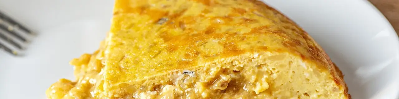 Close-up slice of Spanish tortilla on a white plate with a fork
