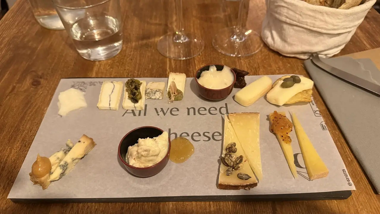 Assorted cheese board with quince paste, capers, honeycomb and jam on a paper-lined tray