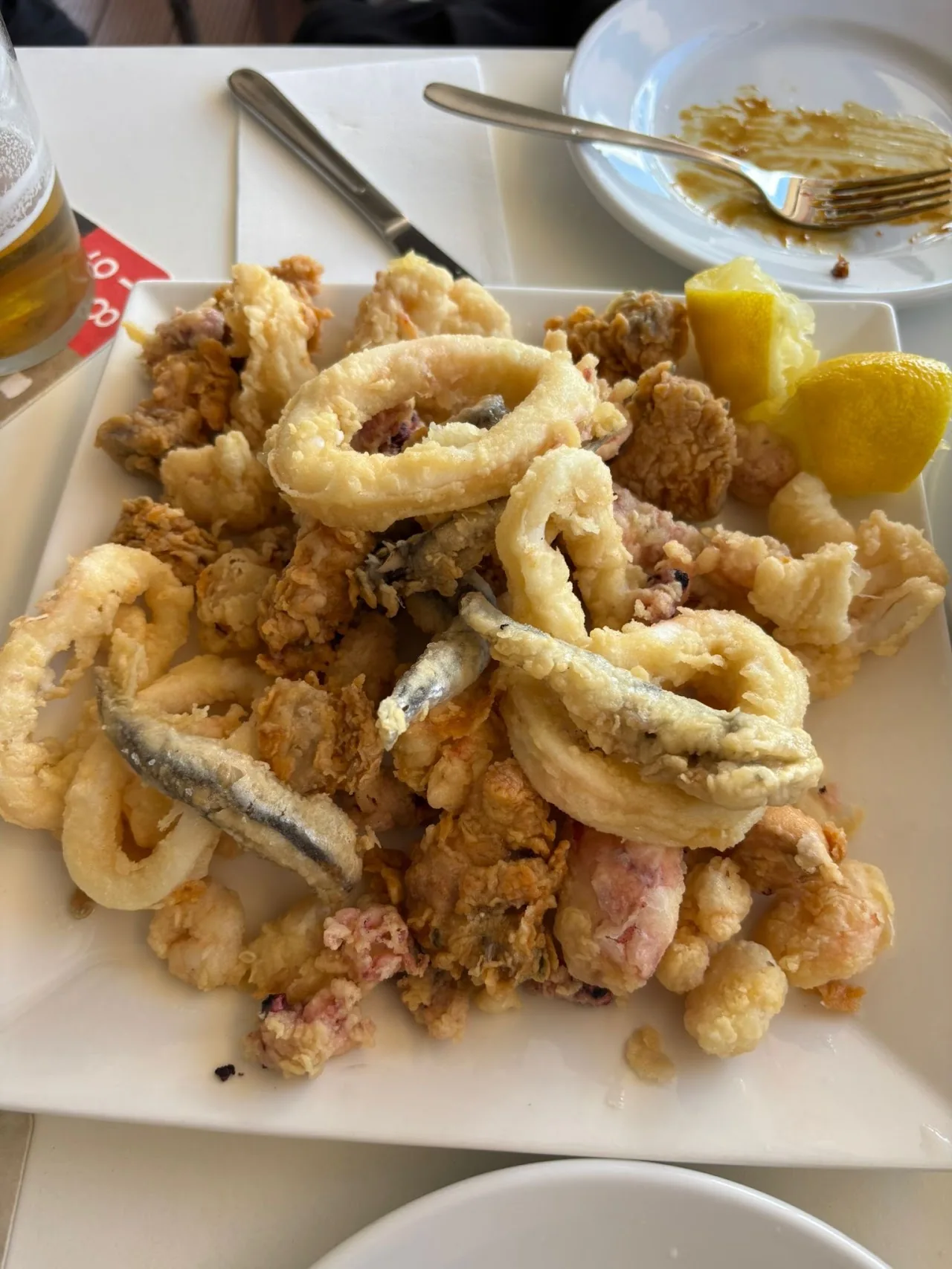 A plate of fried calamari rings and fried anchovies with lemon