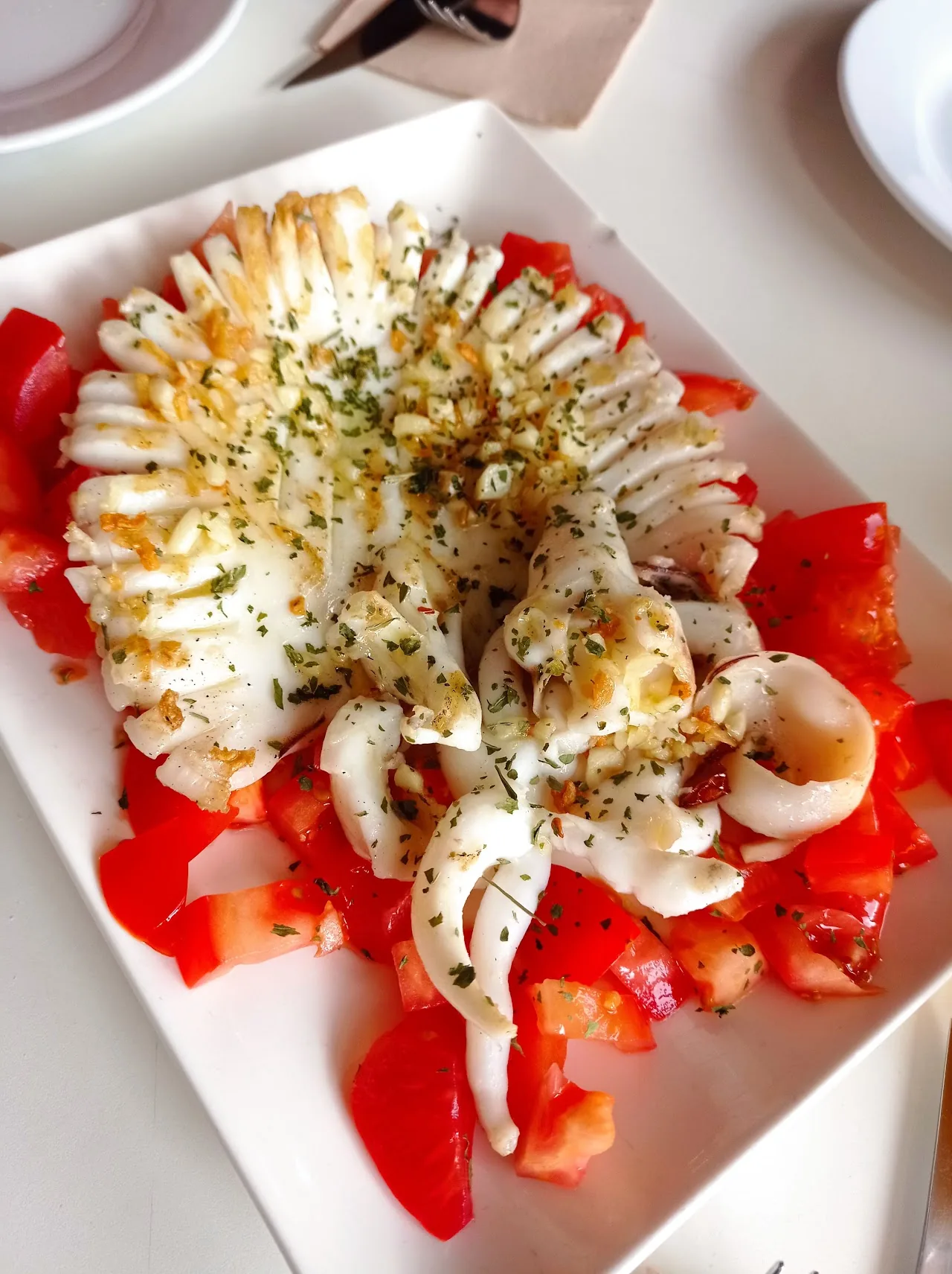 Grilled squid over roasted red peppers with garlic and parsley