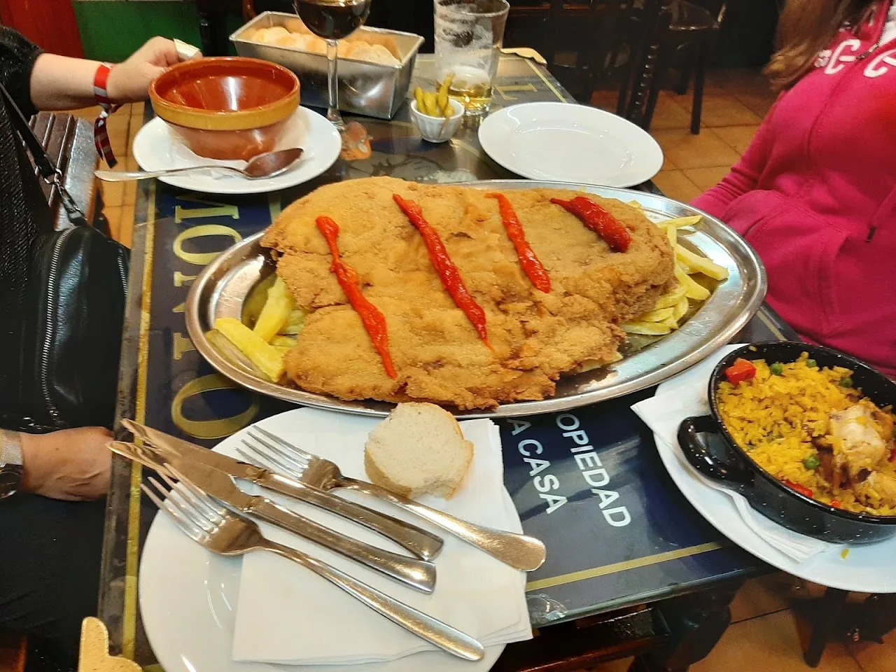 A large breaded veal cutlet topped with red sauce, part of a table spread