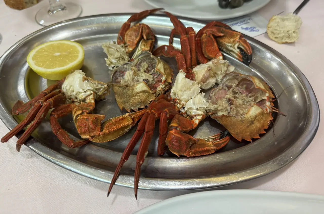 Whole cooked crabs cracked open on a metal platter with lemon half