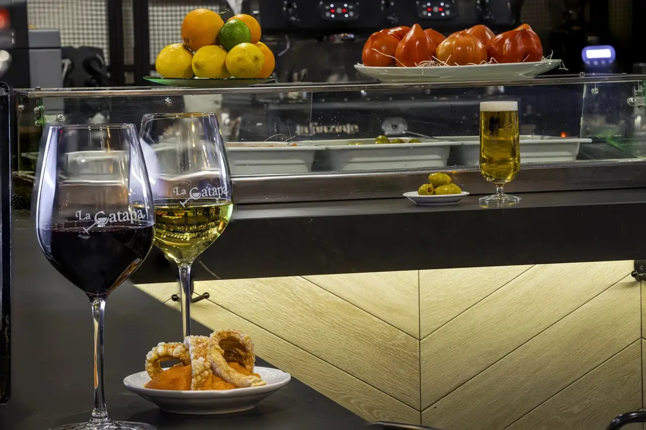 Glasses of red and white wine, a beer and a plate of fried calamari at the bar