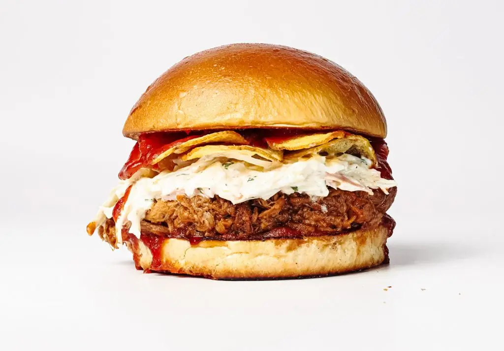 Pulled pork burger topped with coleslaw and potato chips on a brioche bun, La Central Burgers