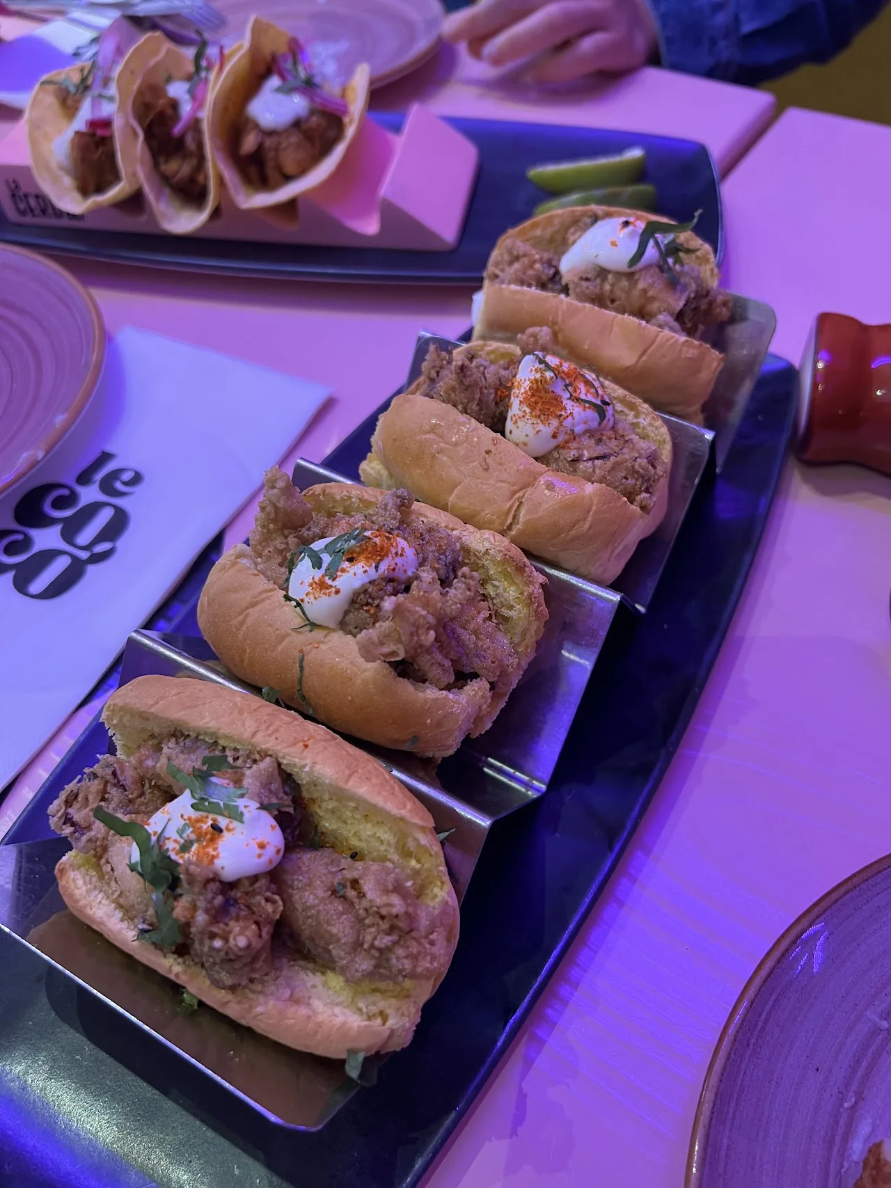 A row of mini sliders topped with meat and garnish
