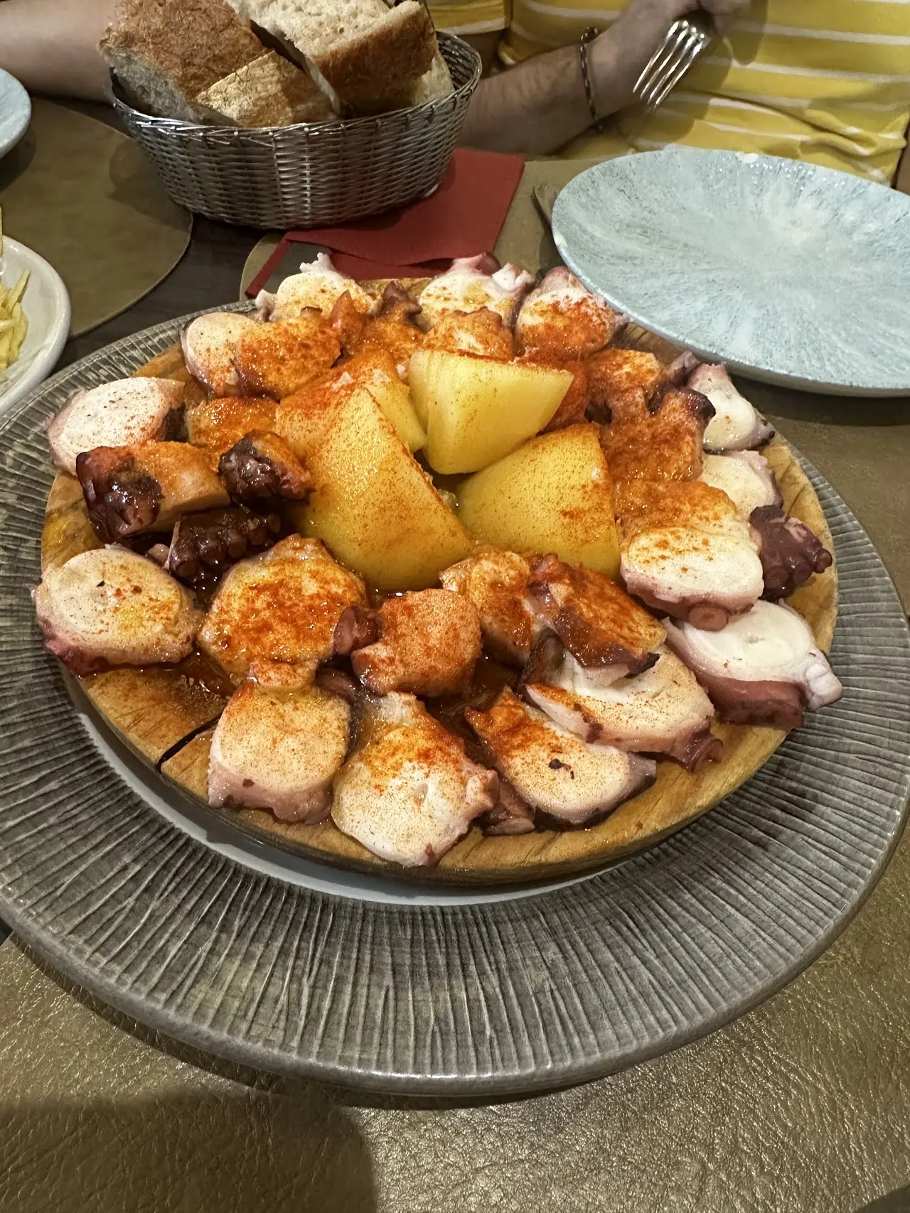 Grilled octopus pieces arranged around roasted potato wedges dusted with paprika