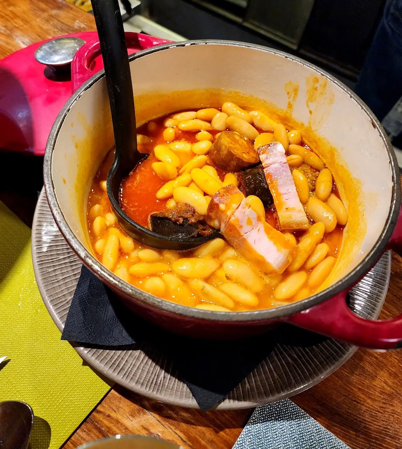 White bean stew with chunks of pork and sausage in a red pot