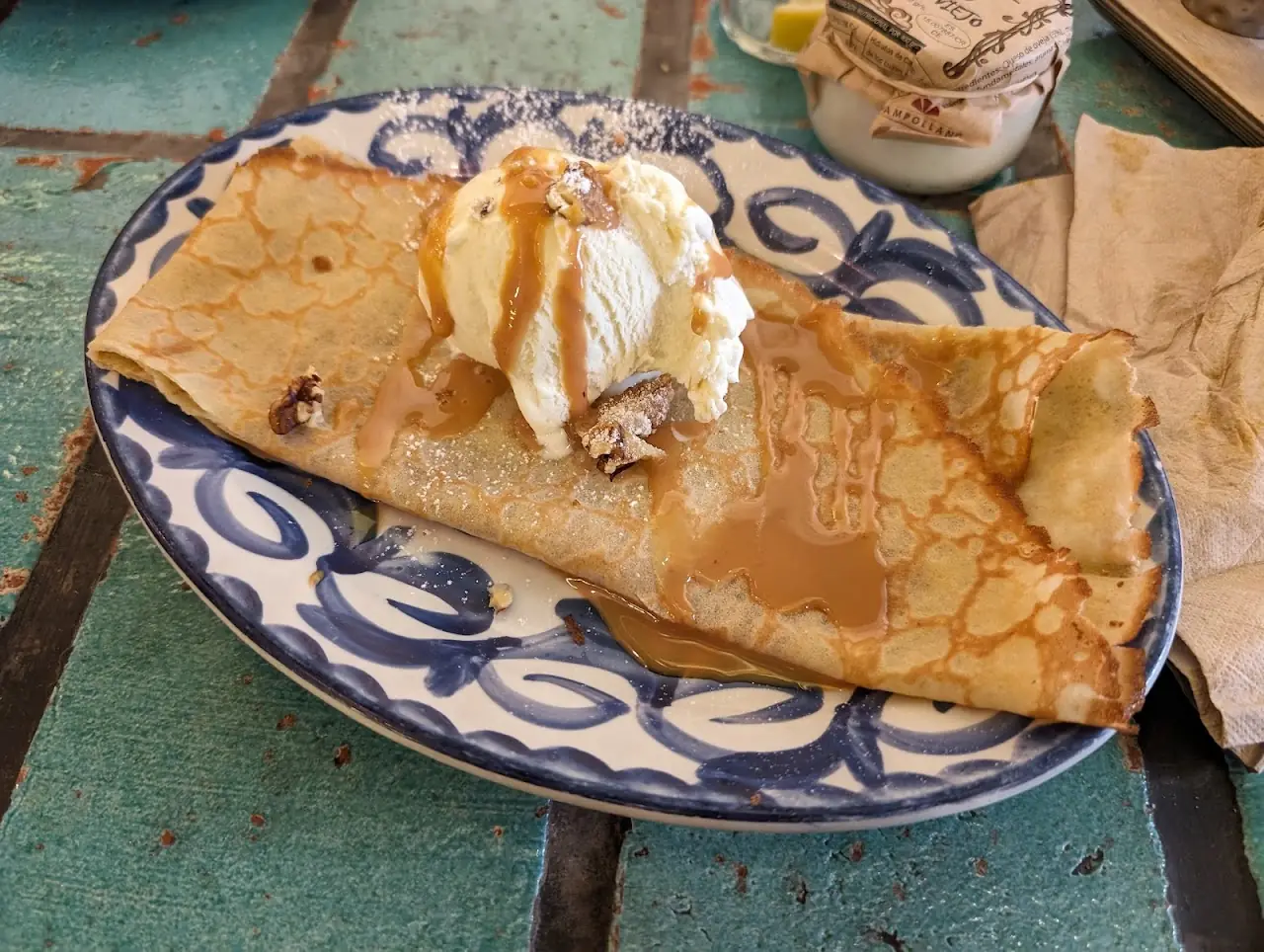 A folded crepe topped with ice cream and caramel sauce