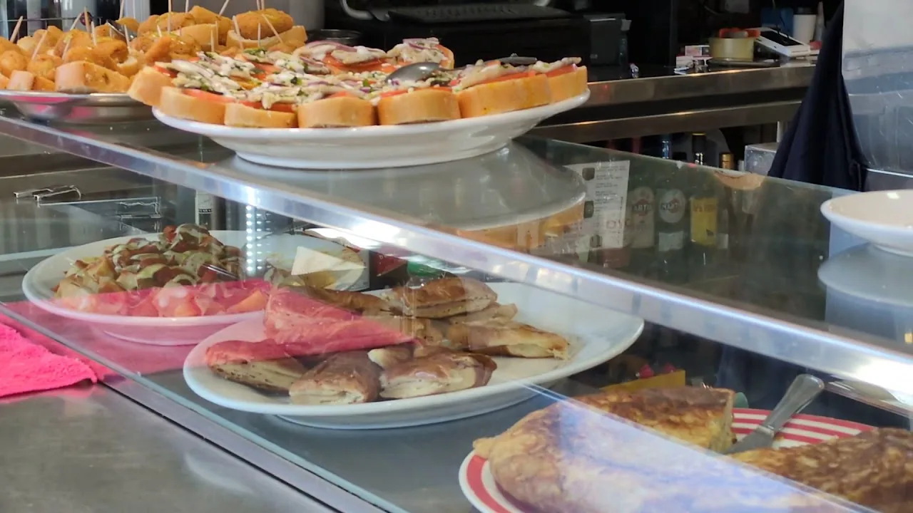 A glass display case of assorted pinchos and tapas on bread