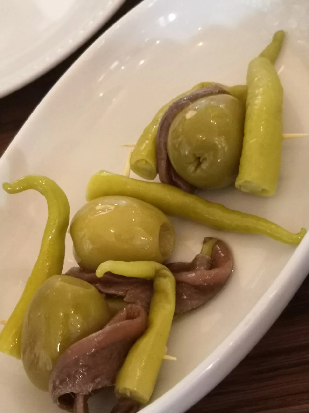 A dish of pickled peppers, olives, and vegetables
