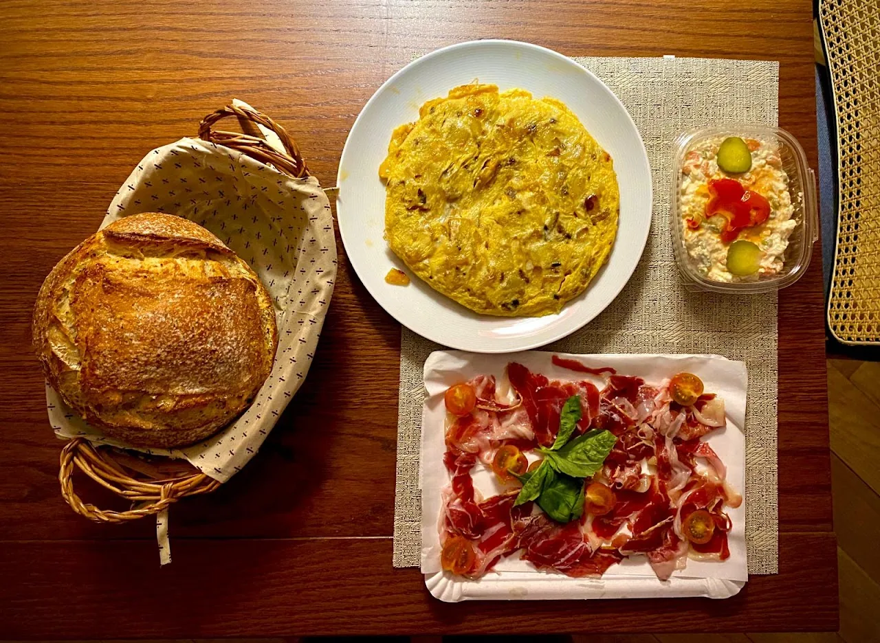 An overhead spread of bread, Spanish tortilla, and sliced ham
