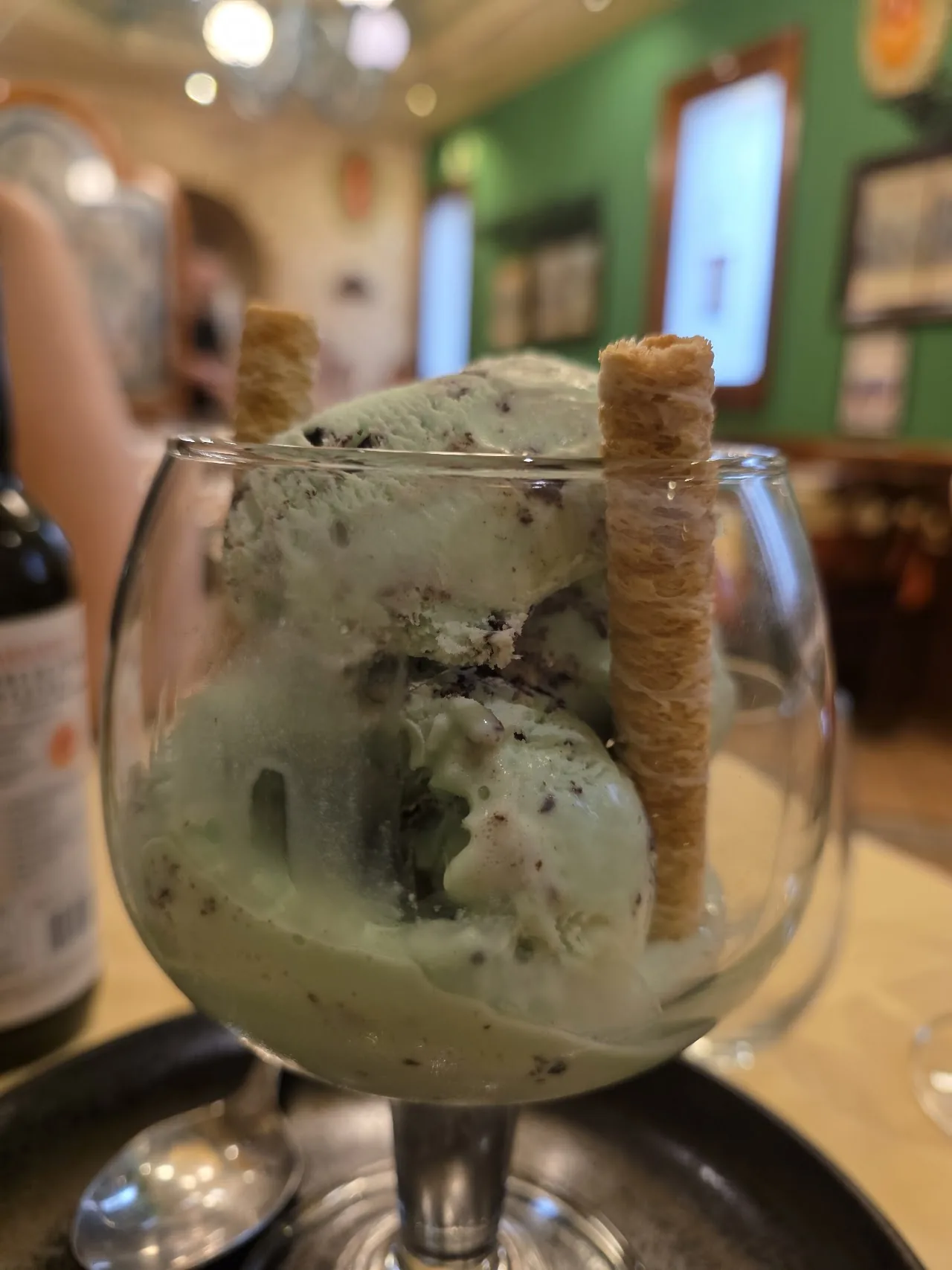 A mint ice cream sundae in a glass with a wafer roll