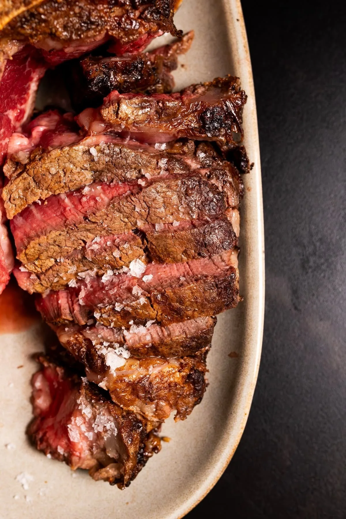 Sliced steak with a pink centre on a long pale plate