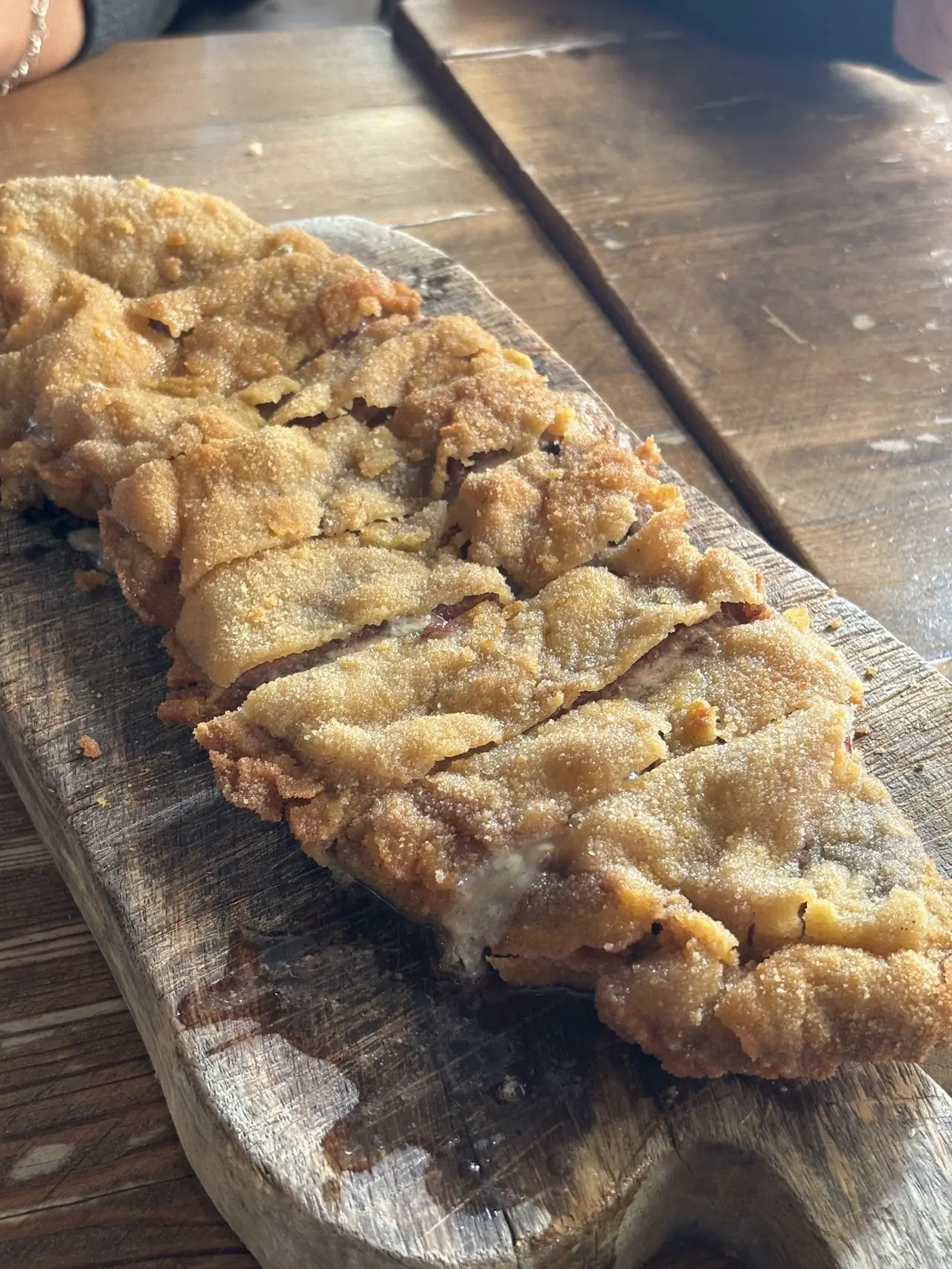 Breaded stuffed cutlet sliced on a wooden board