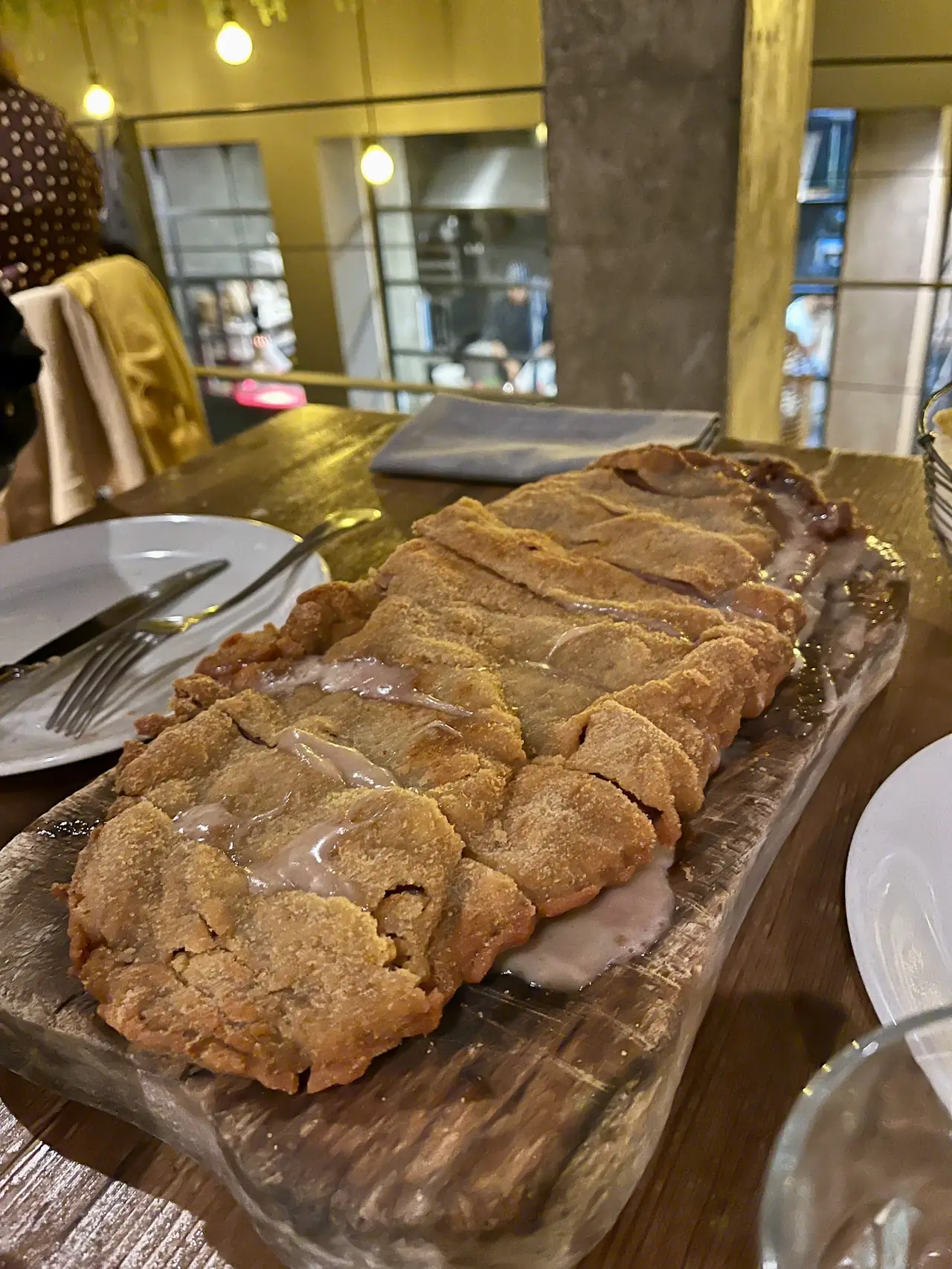 Breaded stuffed cutlet sliced on a wooden serving board at the table