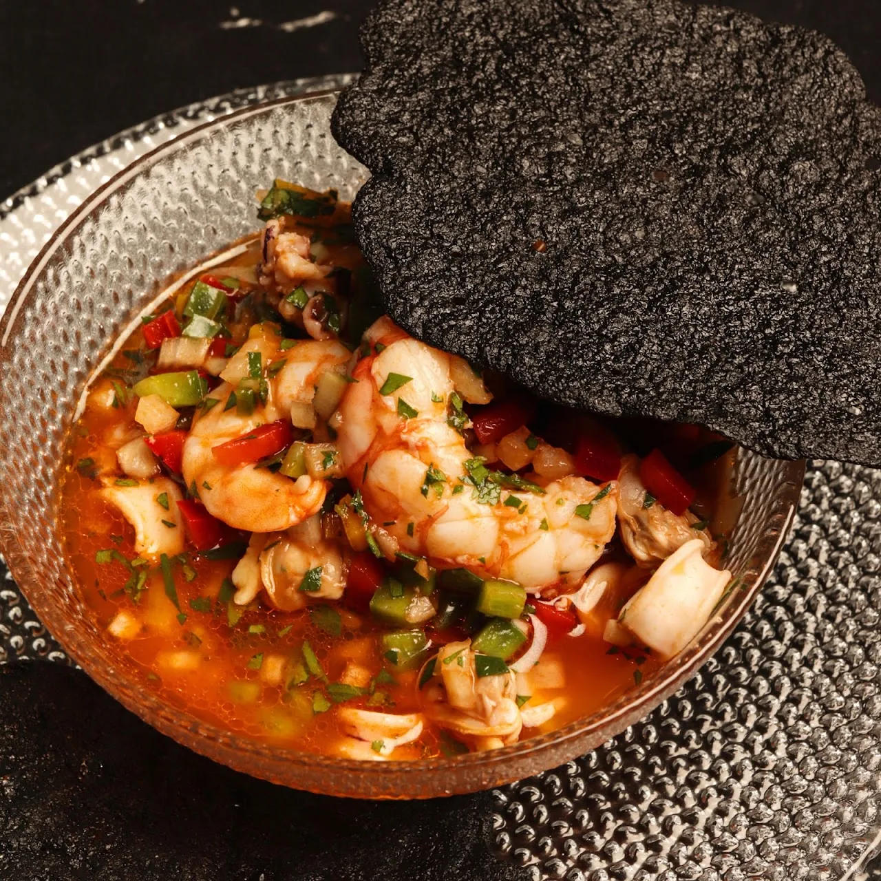 A bowl of shrimp ceviche with a black tortilla chip