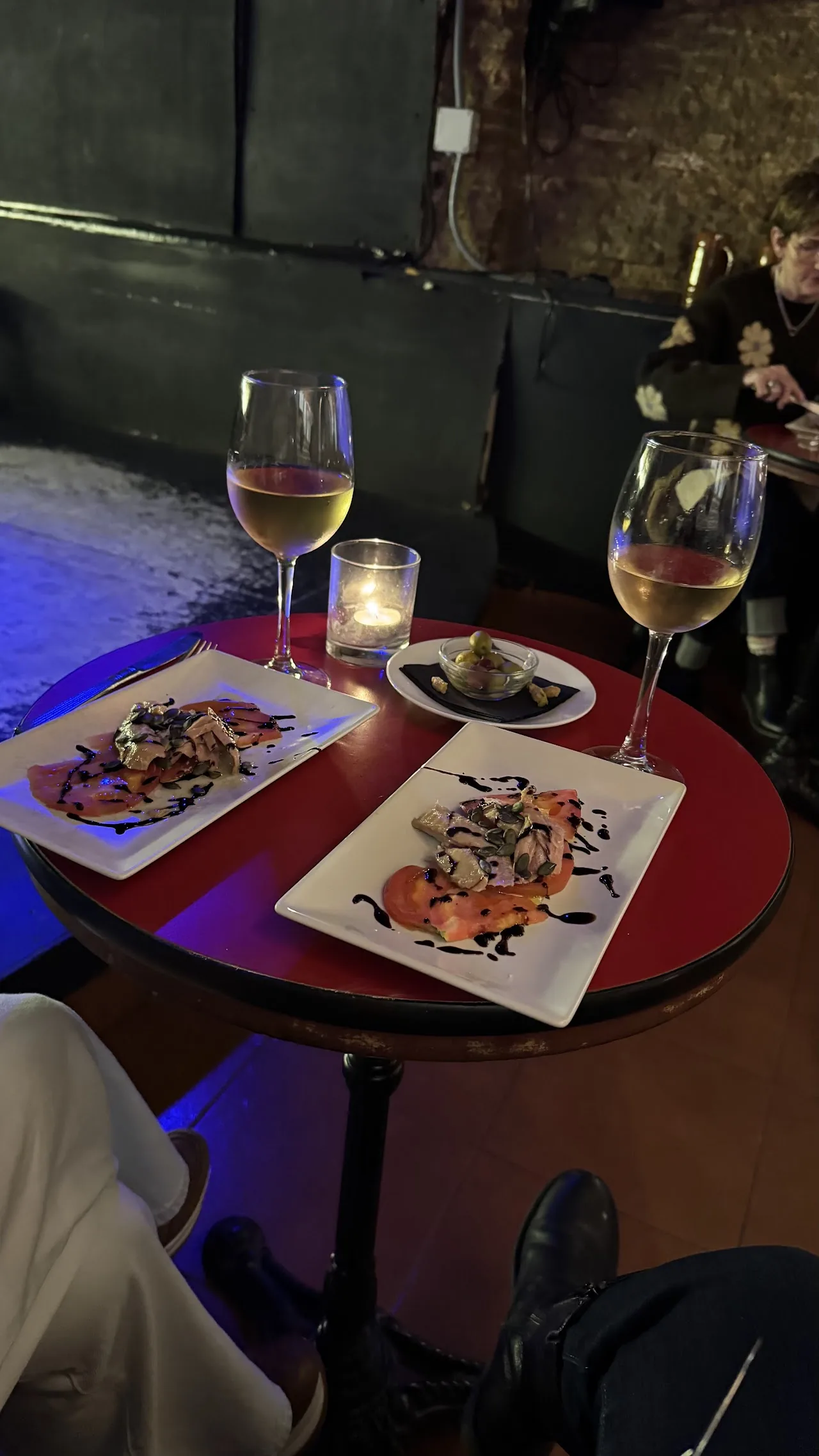 Tapas plates with balsamic drizzle and glasses of white wine on a candlelit table