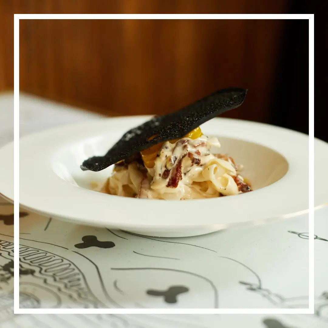 Truffle rigatoni topped with shaved black truffle and small prawns, garnished with microgreens, at La Dama