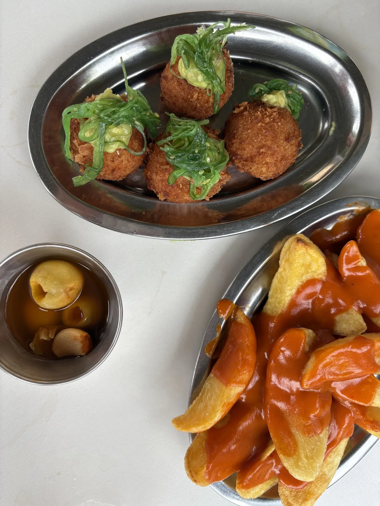 A tray of croquettes, patatas bravas, and marinated olives