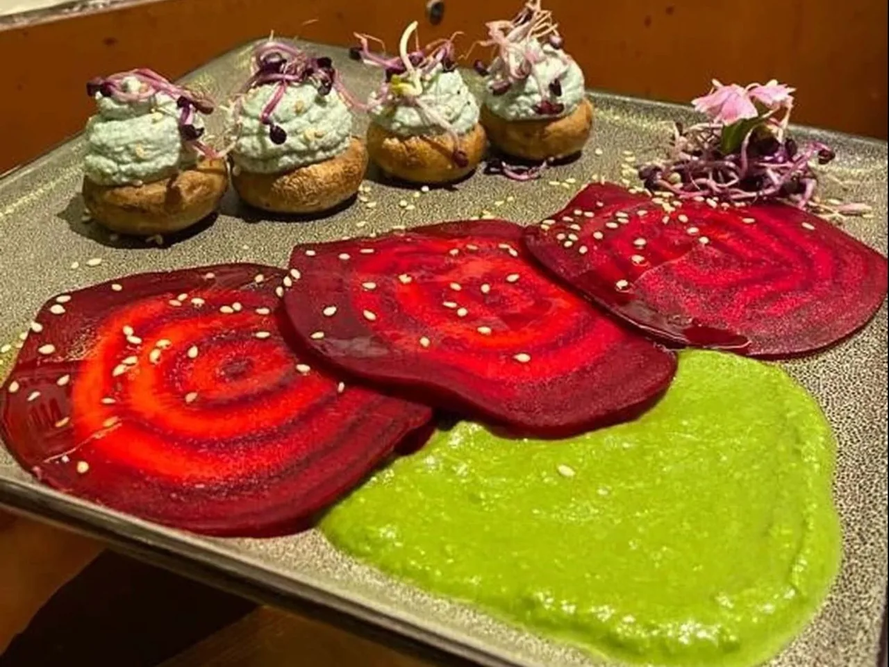 Round slices of red beetroot with a green purée and mushroom caps topped with green cream