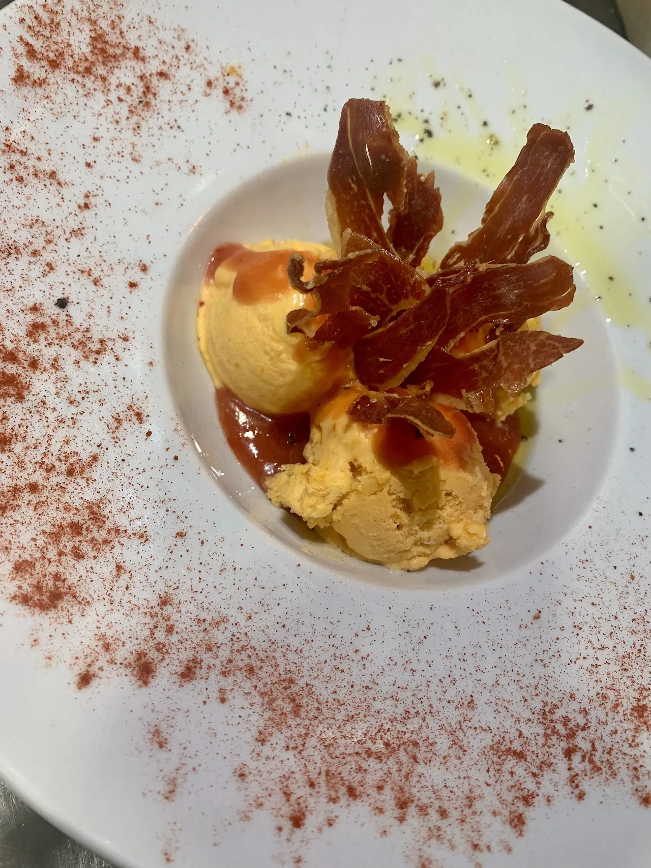 A dessert of ice cream with a caramel shard and cocoa dust