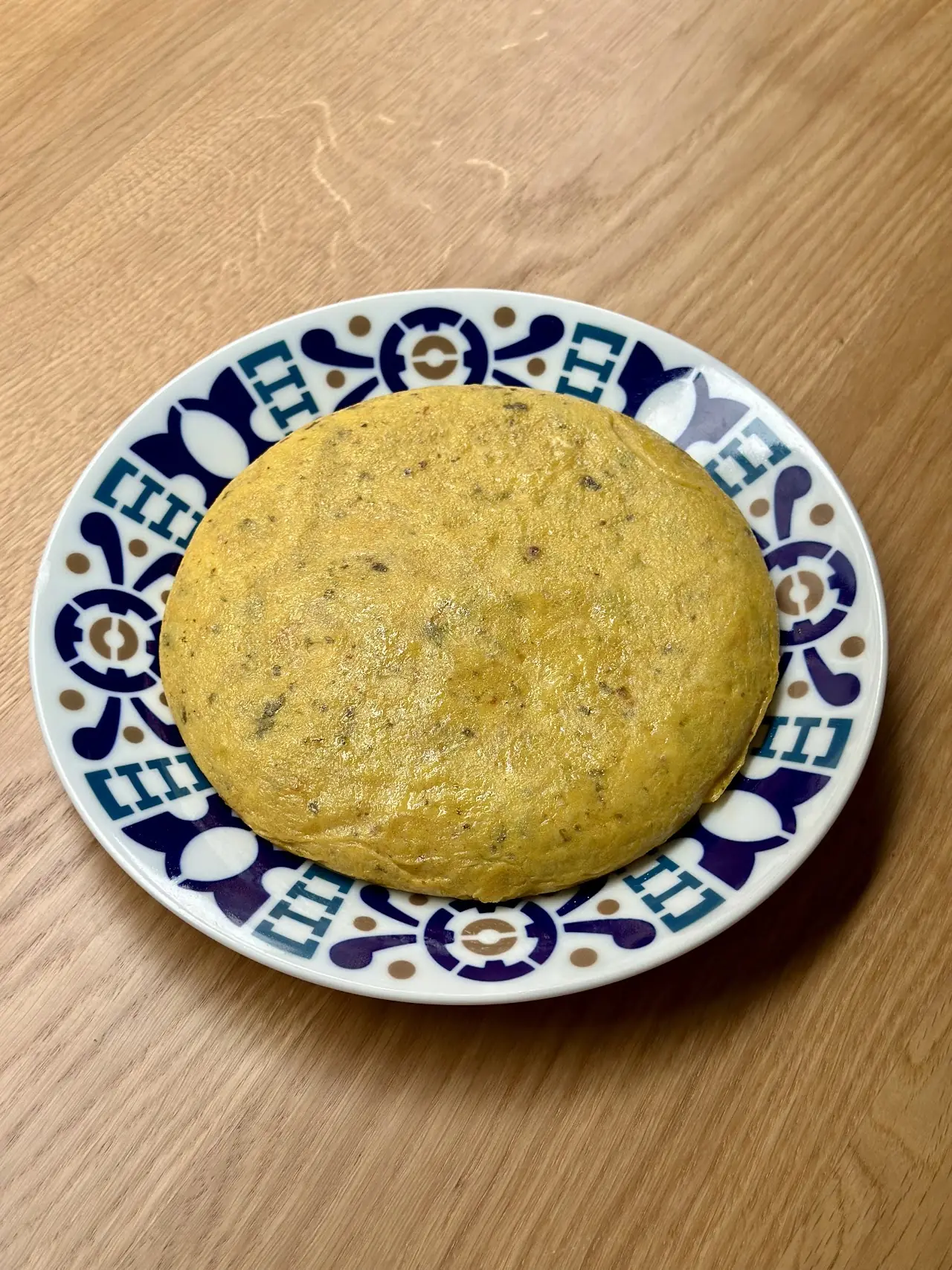 A round Spanish tortilla on a patterned blue and white plate.