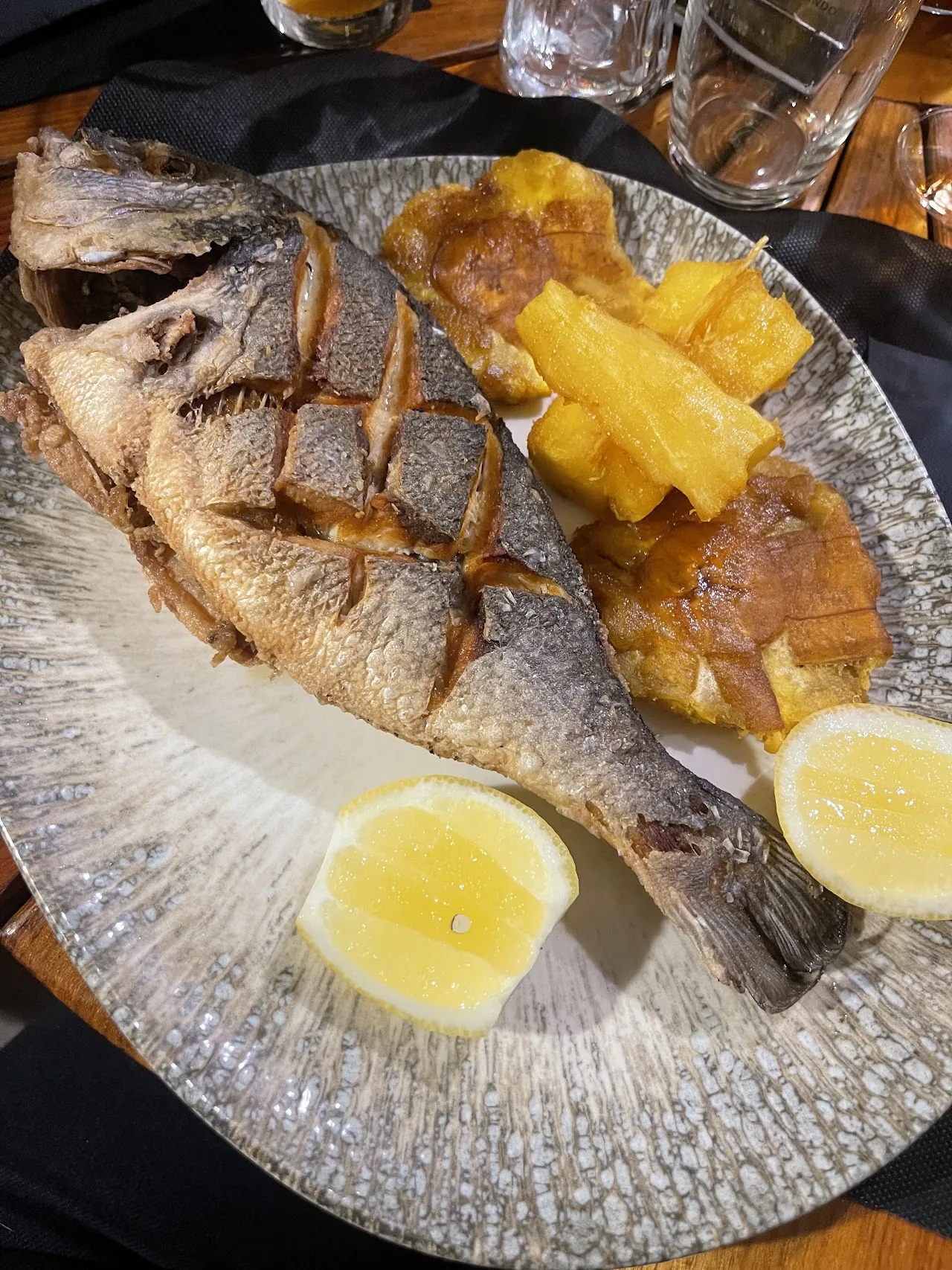 A whole grilled fish with pineapple and lemon wedges