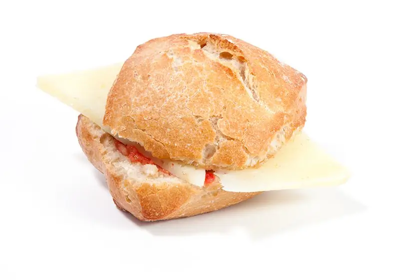 Crusty rustic bread roll filled with sliced cured cheese