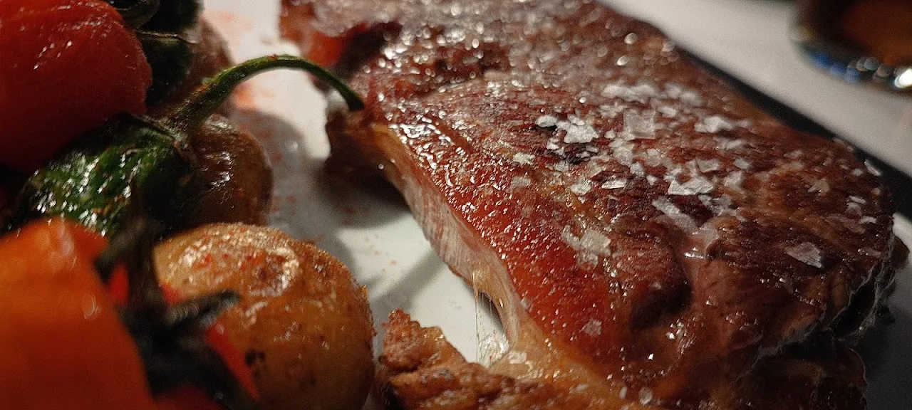 A grilled steak with charred cherry tomatoes and salt