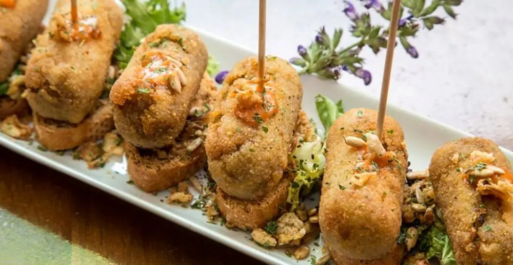 Skewered croquettes on a plate garnished with herbs, at La Granota & Co.