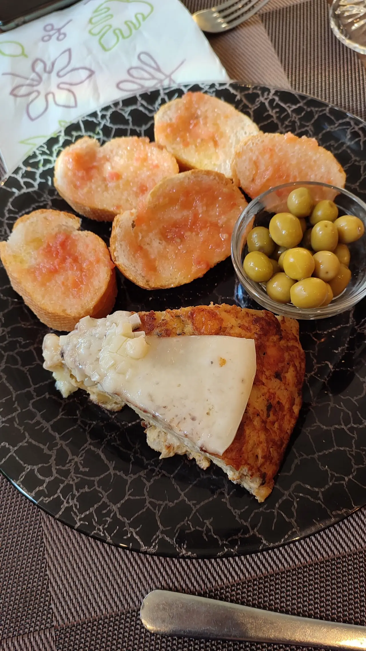 Toasted bread with tomato, a wedge of Spanish tortilla and green olives on a plate, at La Granota & Co.