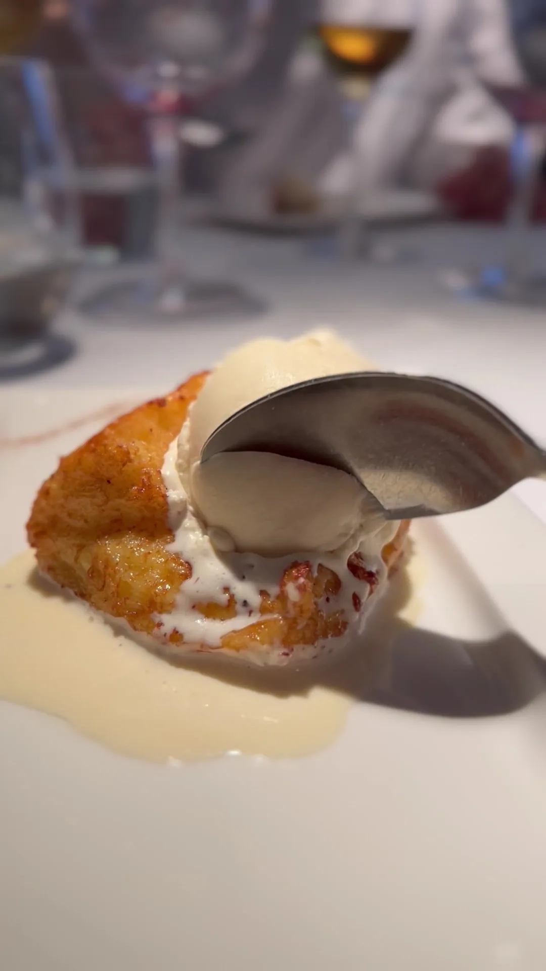 A seared scallop dish with a citrus segment on a white plate