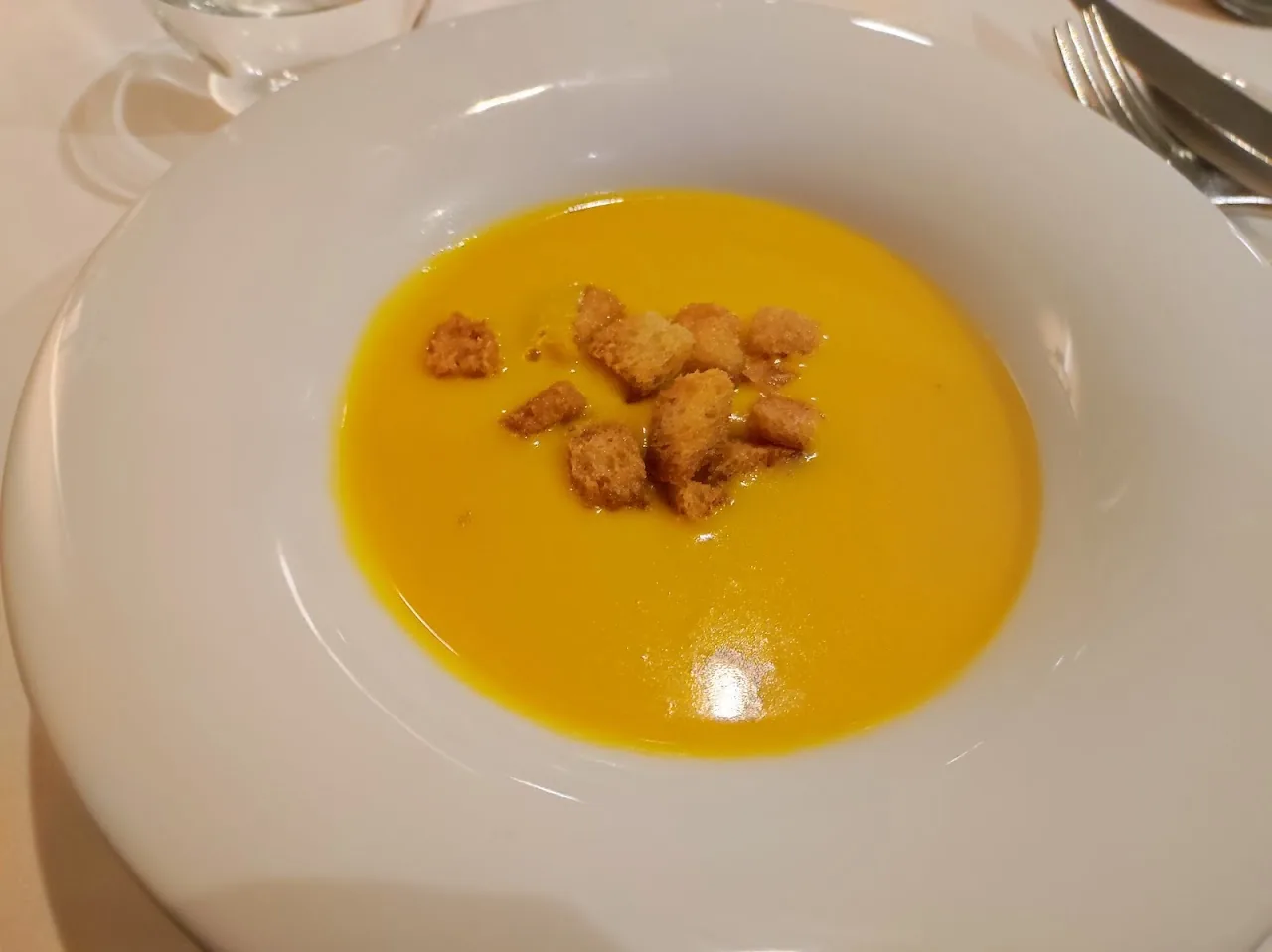 A bright yellow squash soup garnished with croutons