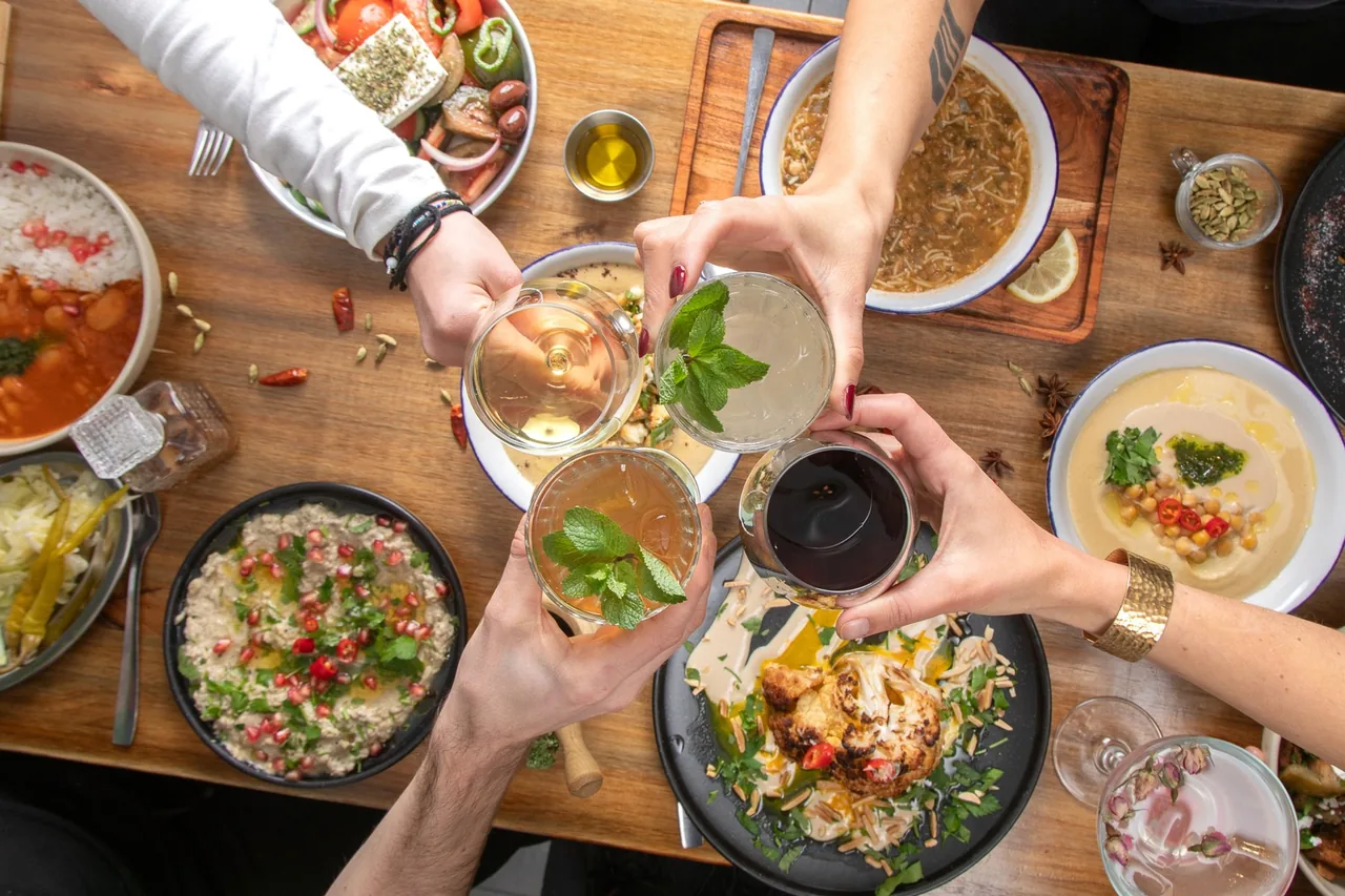 A wooden table filled with plates of hummus, salads and other dishes seen from above